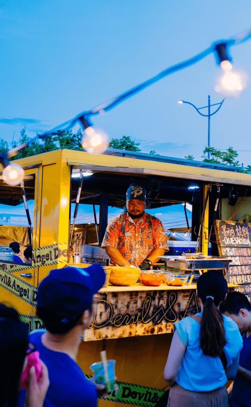 Photo with people standing in front of a food truck. The photo is the image that belongs to the theme Make it economically sound of Business Design Agency.