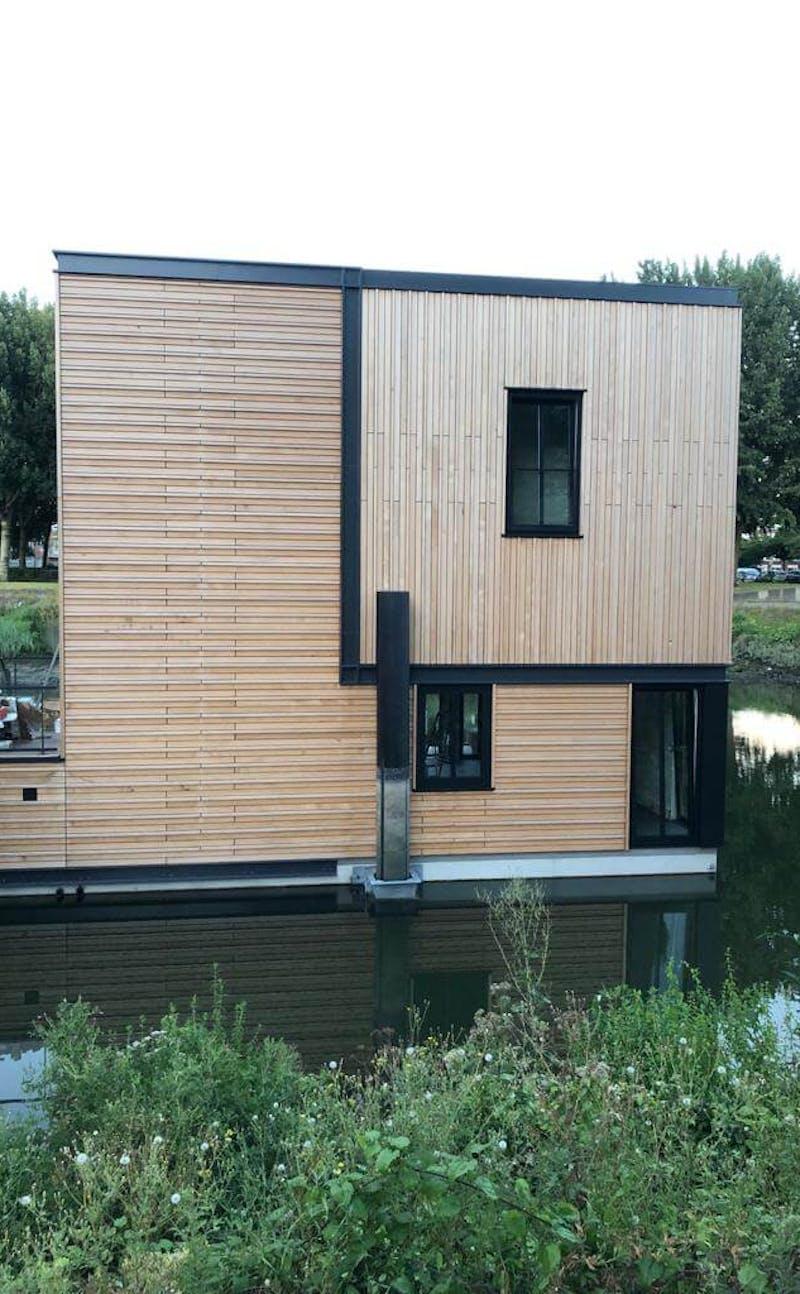 Wooden house on water with green in front of it